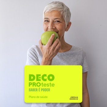 Mulher sorridente, morde maçã verde. Vê-se ainda um cartão